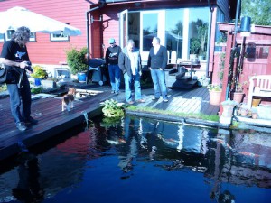 People standing around a koi pond in Norway discussing filtration