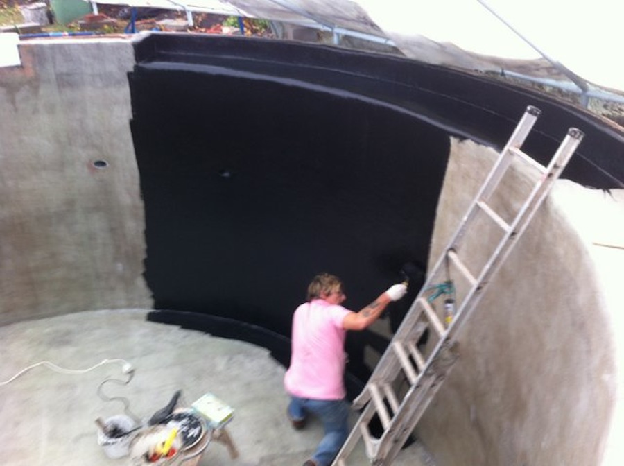 Black resin being applied to the koi pond walls